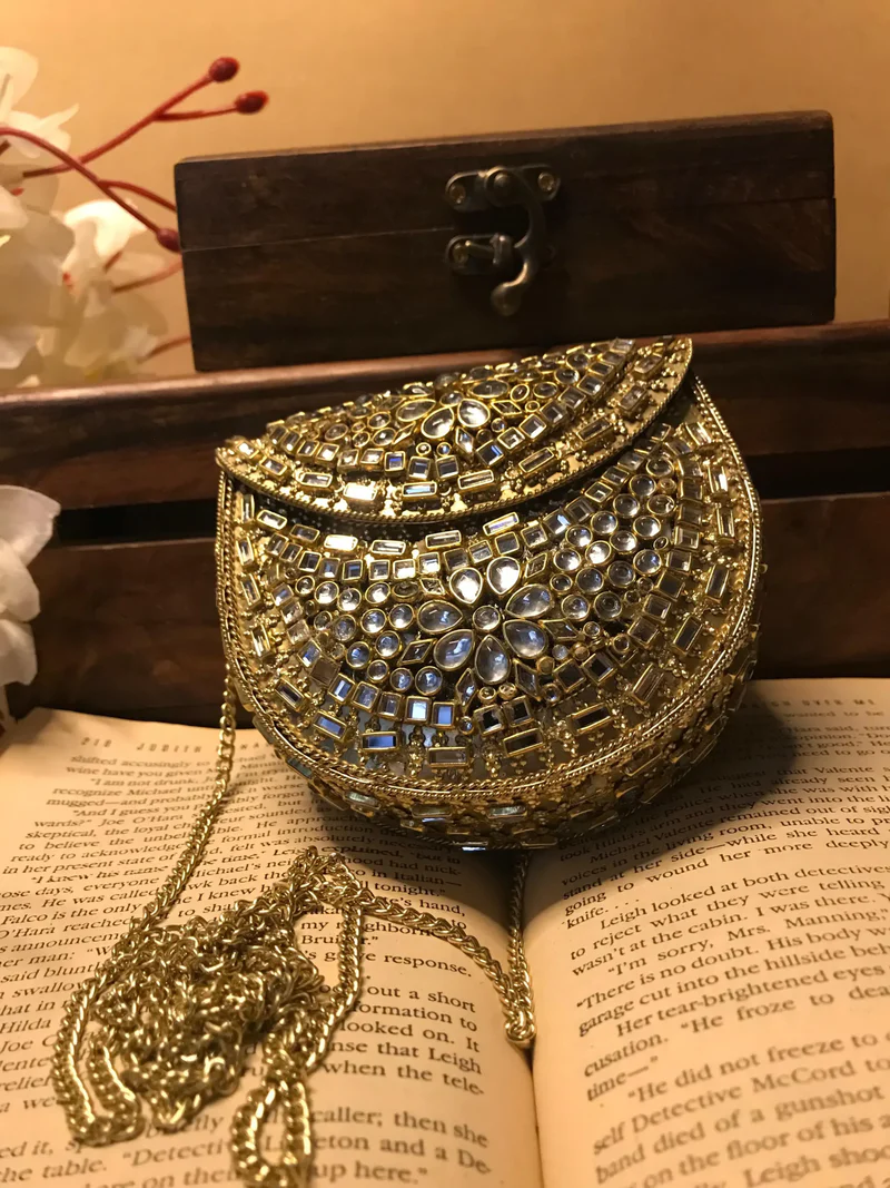 Elevate your style with the Mini Kundan Clutch, featuring exquisite crystal inlays and a regal gold clasp, blending tradition with modern luxury effortlessly.