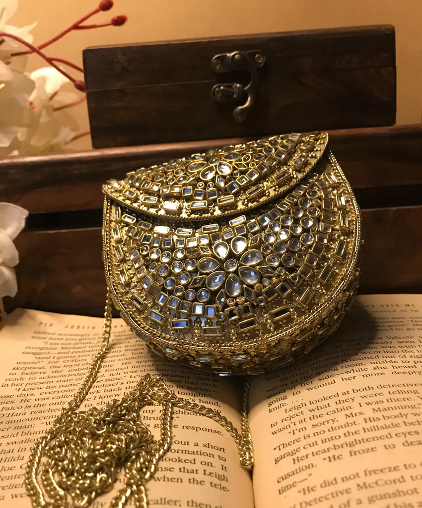 Elevate your style with the Mini Kundan Clutch, featuring exquisite crystal inlays and a regal gold clasp, blending tradition with modern luxury effortlessly.