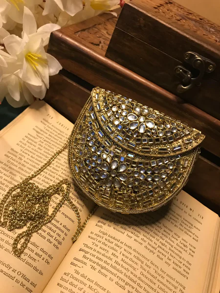 Elevate your style with the Mini Kundan Clutch, featuring exquisite crystal inlays and a regal gold clasp, blending tradition with modern luxury effortlessly.